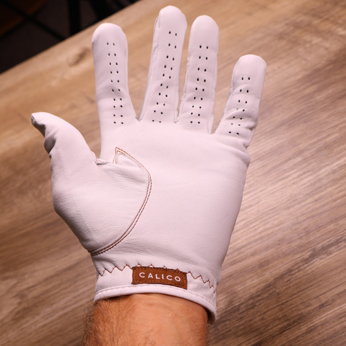 Palm side of the white Calico Golf Glove with copper stitching and Calico wordmark
